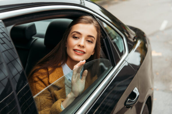 Young woman on back seat of taxi looking in window